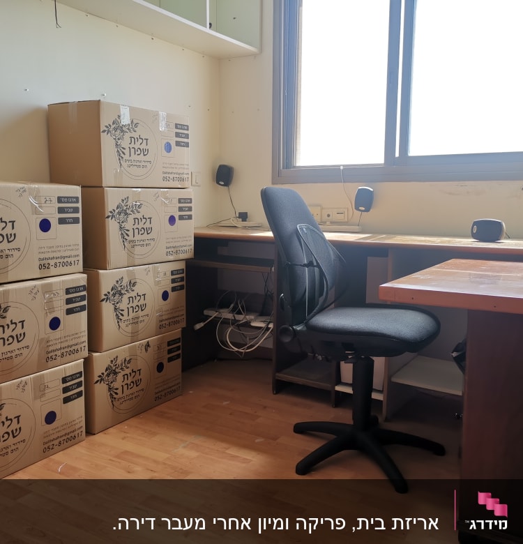 חדר עם קופסאות קרטון מסודרות על הרצפה ליד שולחן עבודה